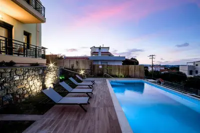 a swimming pool with lounge chairs next to a building at Siena Pool Villa in Koskinou