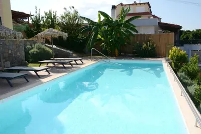 a large blue swimming pool with two picnic tables in a yard at Siena Pool Villa in Koskinou