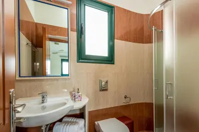 a bathroom with a sink and a toilet and a mirror at Siena Pool Villa in Koskinou
