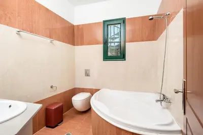 a bathroom with a tub and a toilet and a sink at Siena Pool Villa in Koskinou