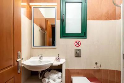 a bathroom with a sink and a mirror and a toilet at Siena Pool Villa in Koskinou