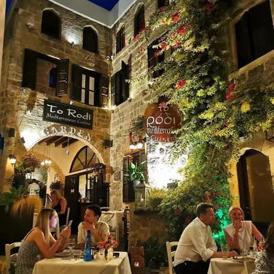 a group of people sitting at tables in a restaurant at To Rodi Apartments in Rhodes Town
