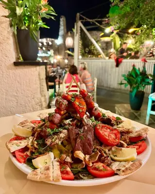 a plate of food with meat and vegetables on a table at To Rodi Apartments in Rhodes Town
