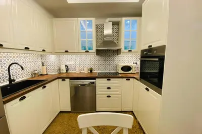 a kitchen with white cabinets and a sink and a chair at Casa del Sud in Apolakkiá