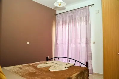 a bedroom with a bed with a pink curtain at ANTONIOS apartments in Archangelos