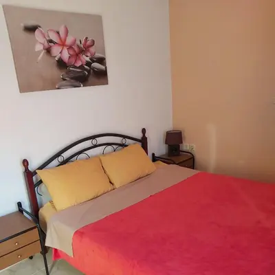 a bedroom with a bed with a red blanket and a painting at ANTONIOS apartments in Archangelos