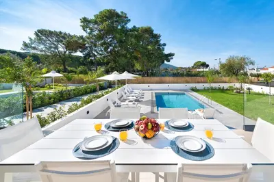 a white dining table and chairs next to a swimming pool at Aurum Villas in Ialyssos