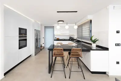a kitchen with a black counter and two stools at Aurum Villas in Ialyssos
