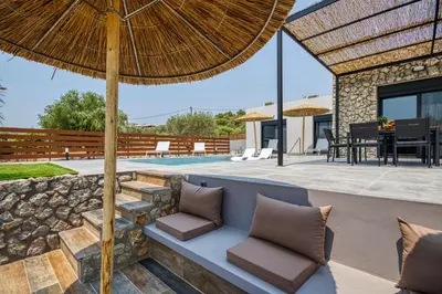 an outdoor patio with a bench and an umbrella at Terra Secreta Luxury Villas in Lardos