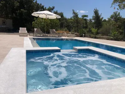 a large swimming pool with an umbrella and chairs at Fiore di Rodi - Private Pool, Jacuzzi and Barbecue in Ialyssos