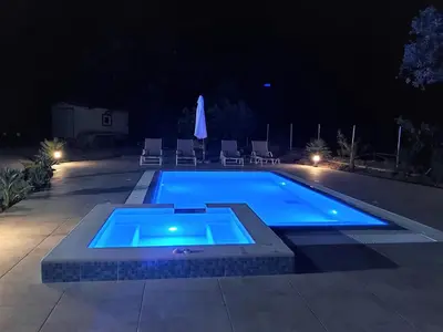 a swimming pool at night with chairs around it at Fiore di Rodi - Private Pool, Jacuzzi and Barbecue in Ialyssos