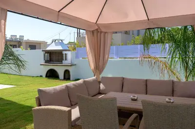 a patio with a couch and a table and umbrella at Villa Costa in Ixia