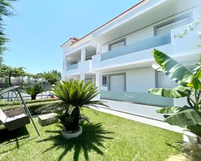 a white building with palm trees in front of it at White House Kokas Luxury Apartments in Kremasti