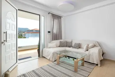 a white living room with a couch and a glass table at White House Kokas Luxury Apartments in Kremasti