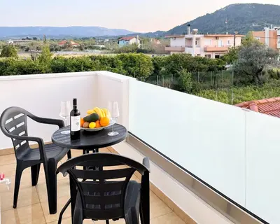 a table with a bowl of fruit on a balcony at White House Kokas Luxury Apartments in Kremasti