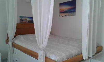 a bed with white curtains in a bedroom at Maria's Little apartment in Rhodes Town