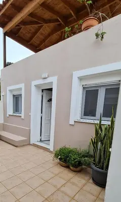 a white house with potted plants on a patio at Maria's Little apartment in Rhodes Town