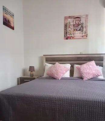 a bedroom with a bed with pink pillows at Family room Rhodes Greece in Ialyssos