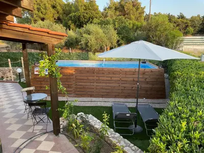 a patio with an umbrella and chairs and a pool at Kiparisia Villa in Phanaes