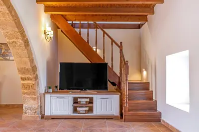 a living room with a tv on a cabinet with a staircase at Bonseye 2Floor, sea, nature & relax in Kalavárda