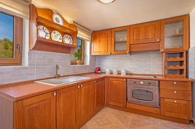 a kitchen with wooden cabinets and a sink at Bonseye 2Floor, sea, nature & relax in Kalavárda