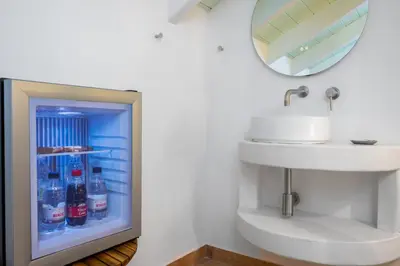 a bathroom with a sink and a refrigerator with soda bottles at Villa Theoni in Halki