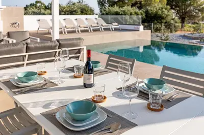 a table with a bottle of wine and glasses next to a pool at Villa AmberBlue Pefkos in Pefki Rhodes