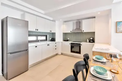 a kitchen with white cabinets and a stainless steel refrigerator at Villa AmberBlue Pefkos in Pefki Rhodes
