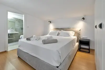 a bedroom with a large white bed and a bathroom at Villa AmberBlue Pefkos in Pefki Rhodes
