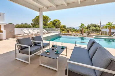a patio with a couch and chairs next to a swimming pool at Villa AmberBlue Pefkos in Pefki Rhodes