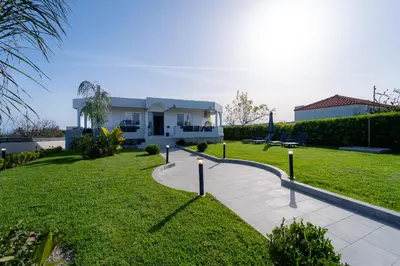 a villa with a lawn in front of a house at Villa Giota Luxury Living with Private Jacuzzi and Free Car in Theologos