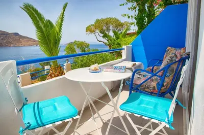 a table and chairs on a balcony with the ocean at Antoniadi Rooms in Livadia
