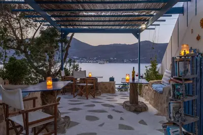 a patio with tables and chairs and a view of the water at Antoniadi Rooms in Livadia