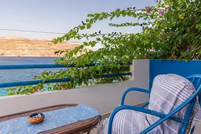 a chair on a balcony with a view of the water at Antoniadi Rooms in Livadia
