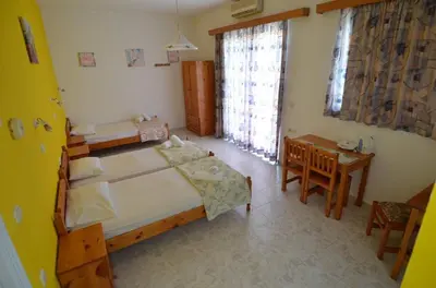 a bedroom with two beds and a table and a window at Marianthi Studios Stegna in Archangelos