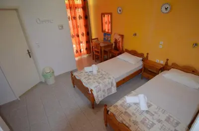 a bedroom with two beds and a table and chairs at Marianthi Studios Stegna in Archangelos