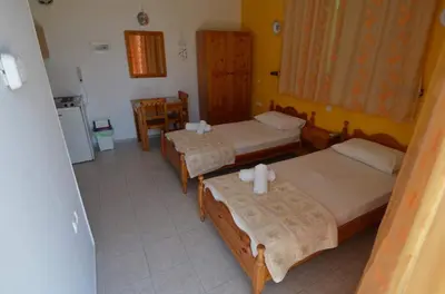 a hotel room with three beds and a table at Marianthi Studios Stegna in Archangelos