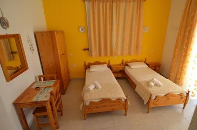a room with two beds and a table and a table at Marianthi Studios Stegna in Archangelos