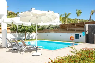a swimming pool with two chairs and an umbrella and a pool at Rhodian Dunes Villas with Private Pool in Kiotari