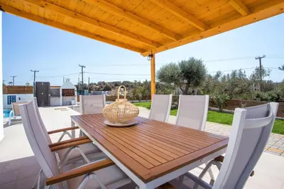 a wooden table and chairs on a patio at Rhodian Dunes Villas with Private Pool in Kiotari