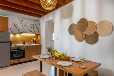 a kitchen with a wooden table with plates and wine glasses at Voyaz Boutique Apartments & Suites -Old Town in Rhodes Town