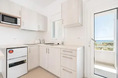 a kitchen with white cabinets and a window at CrossRhodes Villas in Pefki Rhodes