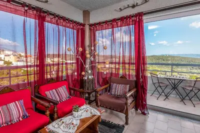 a living room with red chairs and a large window at Thomas Hotel in Monólithos