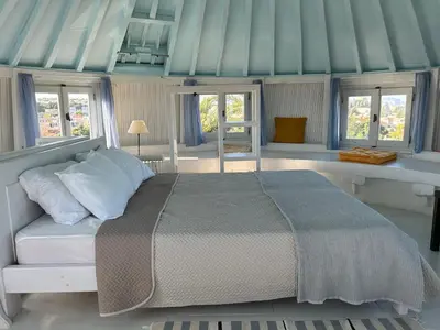 a bedroom with a bed in a room with windows at A medieval windmill tower 2bedrooms in the heart of old town with magnificent panoramic seaview and cityview in Rhodes Town