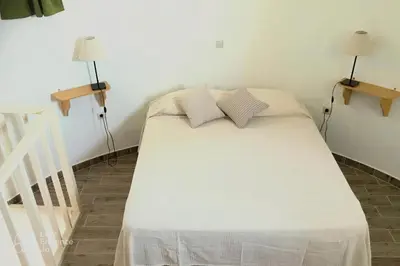 a white bed in a room with two lamps at A medieval windmill tower 2bedrooms in the heart of old town with magnificent panoramic seaview and cityview in Rhodes Town