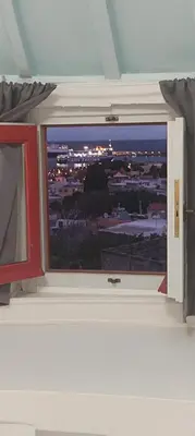 a window in a room with a view of a city at A medieval windmill tower 2bedrooms in the heart of old town with magnificent panoramic seaview and cityview in Rhodes Town
