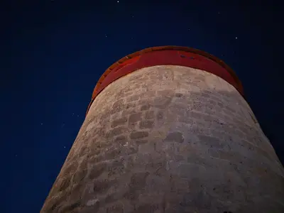 a brick tower with a red roof at night at A medieval windmill tower 2bedrooms in the heart of old town with magnificent panoramic seaview and cityview in Rhodes Town