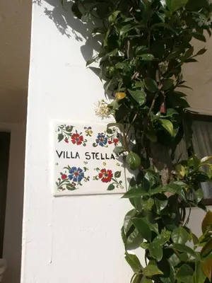 a sign for villa stella on a wall with a plant at Villa Stella Family House in Pefki Rhodes