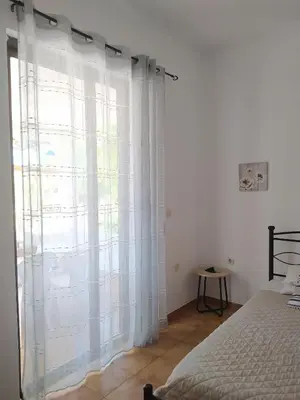 a bedroom with a window with white curtains at Villa Stella Family House in Pefki Rhodes