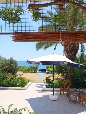 a patio with an umbrella and chairs and the ocean at Villa Stella Family House in Pefki Rhodes